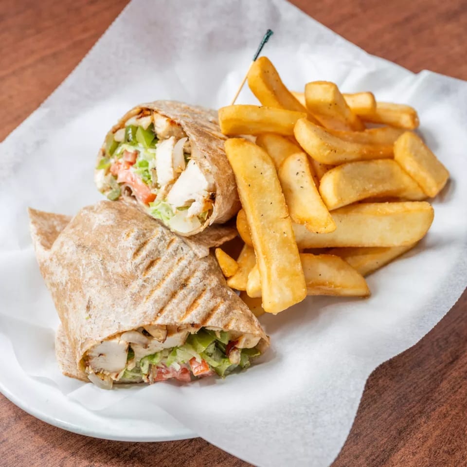 Grilled chicken wrap with lettuce and tomato, served with a side of thick-cut french fries.