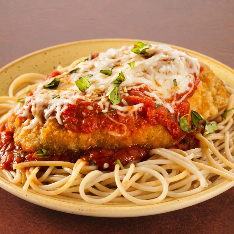 Chicken parmesan with melted mozzarella, red sauce, and fresh basil, served over spaghetti.