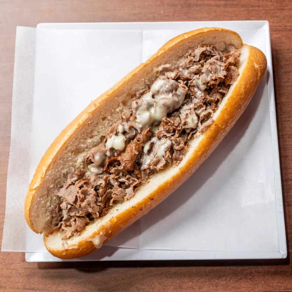Cheesesteak sandwich with shredded steak and melted cheese on a long roll.